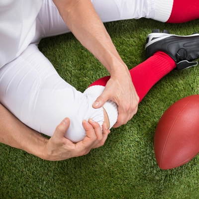 A football player holding their knee on the ground after an injury